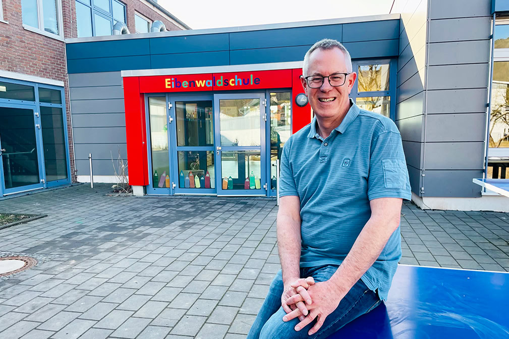 Thomas Brandes sitzt vor einer Schule